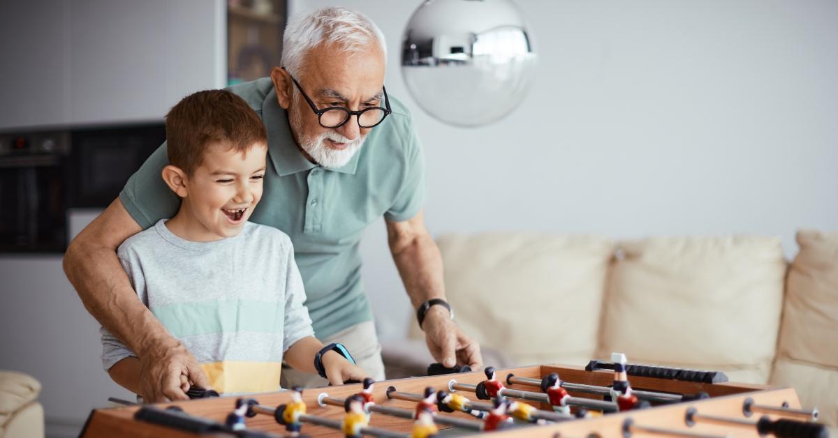 A grandfather and his grandson play table football.