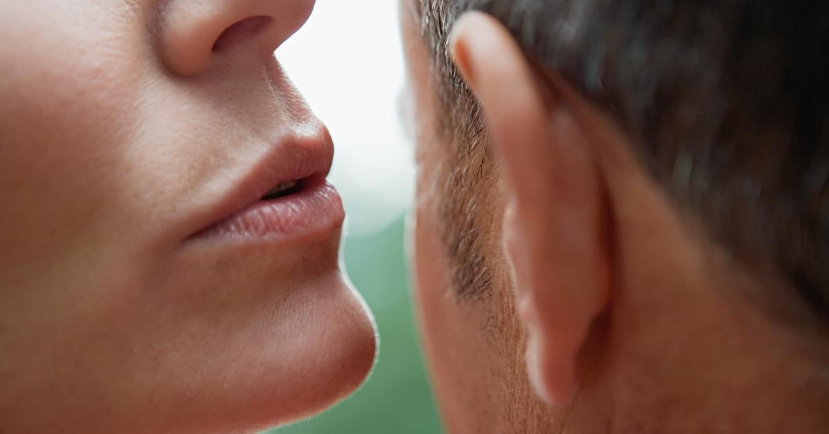 up-close woman whispers in man's ear