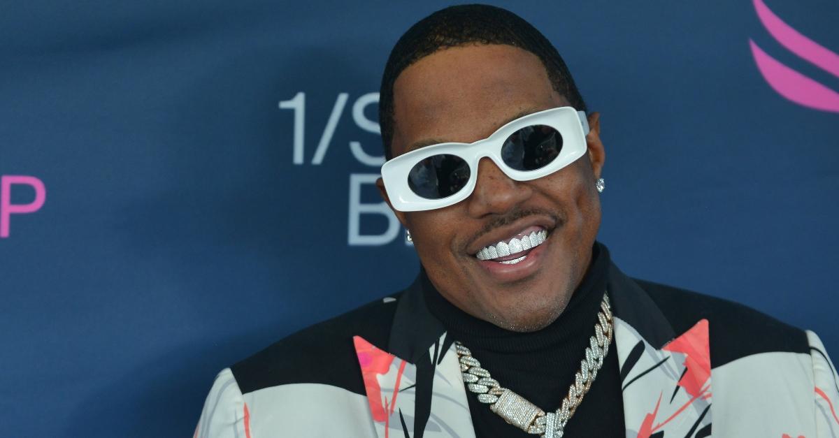 MA$E wears a grill and white sunglasses and smiles while he attends the 2022 Pegasus World Cup at Gulfstream on January 29, 2022 in Hallandale, Florida