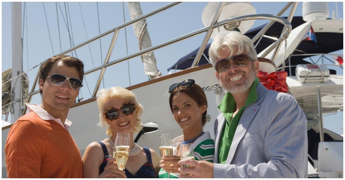 (l-r): A group of people toasting champagne on a yacht