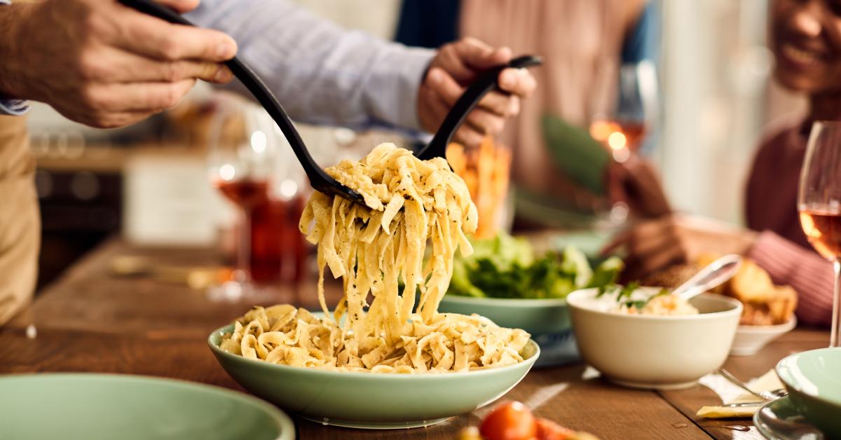 A person serves pasta at their dinner table.