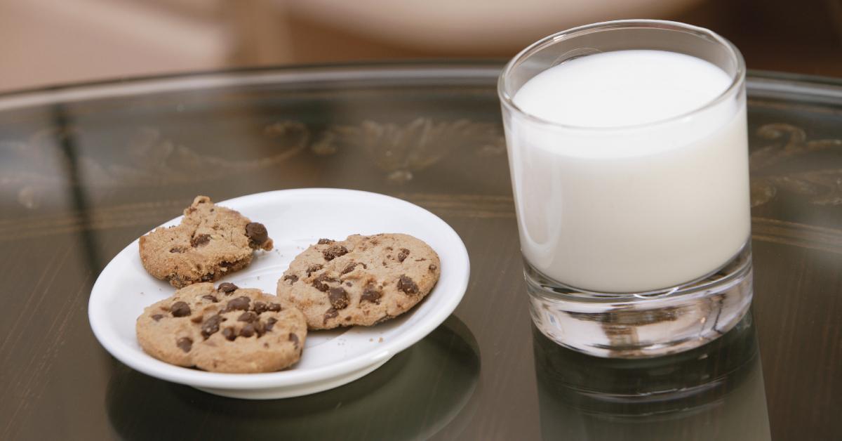 A plate of chocolate chip cookies alongside a glass of milk.