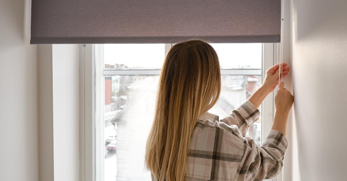 woman opens window blinds
