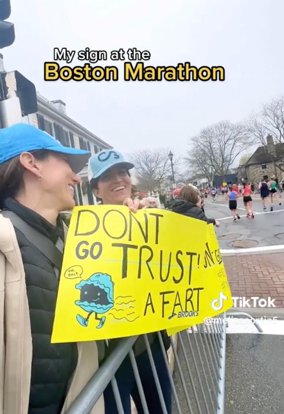 Una mujer con un cartel que dice "No te fíes de un pedo" en un maratón